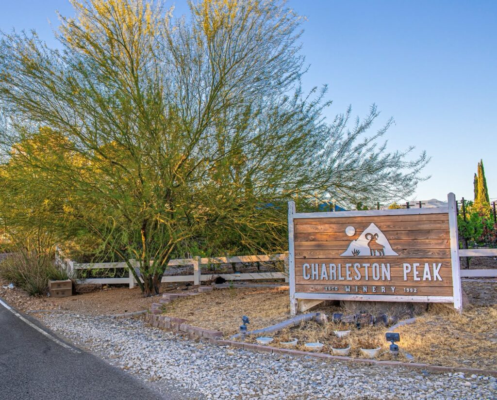 Entrance sign and fence located next to a driveway that leads up to Charleston Peak Winery